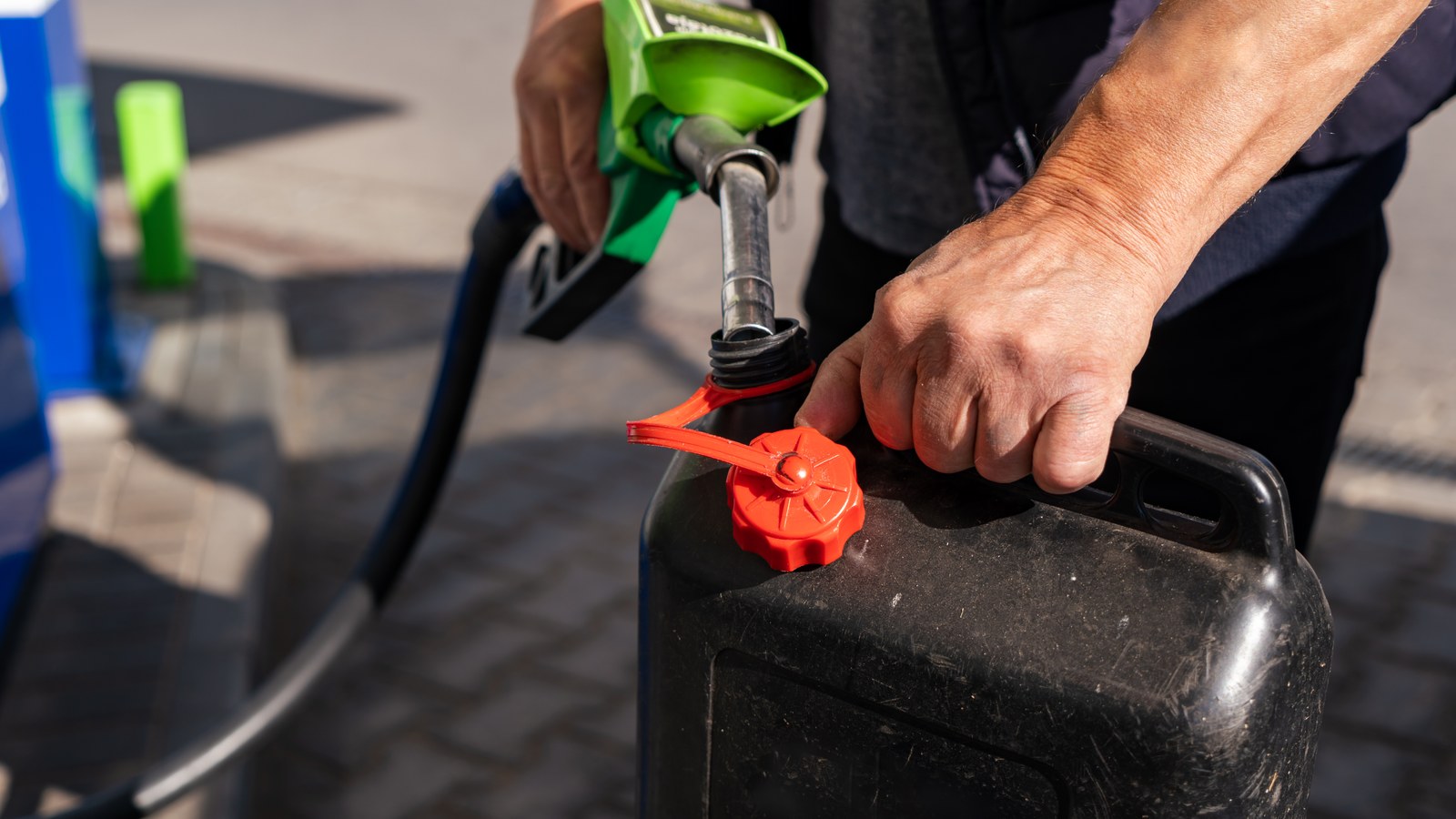 Iemand vult een brandstofjerrycan aan de pomp van een tankstation